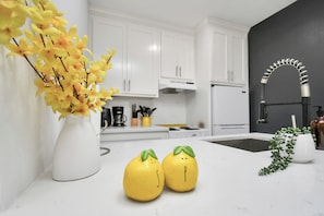 A modern kitchen with white cabinets, a black faucet, and a vase with yellow flowers. - Arbor Flats #6 in the Heart of Houston (Houston)