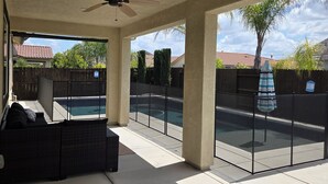 Ein überdachter Außenbereich mit Deckenventilator, Pool und Blick auf eine Wohngegend.