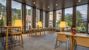Un espace de restauration intérieur moderne, doté de grandes fenêtres, de tables et de chaises en bois.