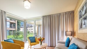 Un salon moderne avec un canapé, deux fauteuils, une petite table ronde et un vase de fleurs.