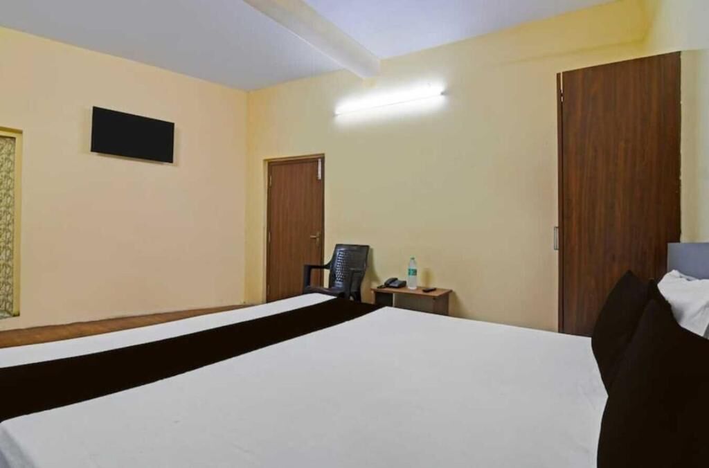 A hotel room with a large bed, a desk with a chair, a television, and a wardrobe.