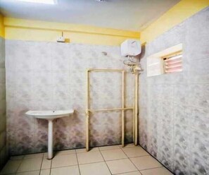 A bathroom with a pedestal sink, a shower enclosure, and a window with blinds. - Dear Hotel (Kolkata)