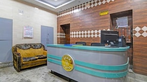 A reception desk with a 'Dear Hotel' logo, a check-out counter, a sofa, and a calendar on the wall. - Dear Hotel (Kolkata)