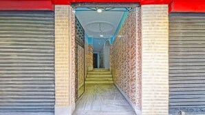 A corridor with closed shutters, patterned walls, and a staircase leading to a room. - Dear Hotel (Kolkata)