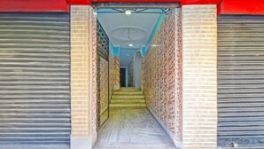 A corridor with closed shutters, patterned walls, and a staircase leading to a room. - Dear Hotel (Kolkata)