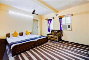 A bedroom with a bed, a sofa, a ceiling fan, and an air conditioning unit. - Dear Hotel (Kolkata)
