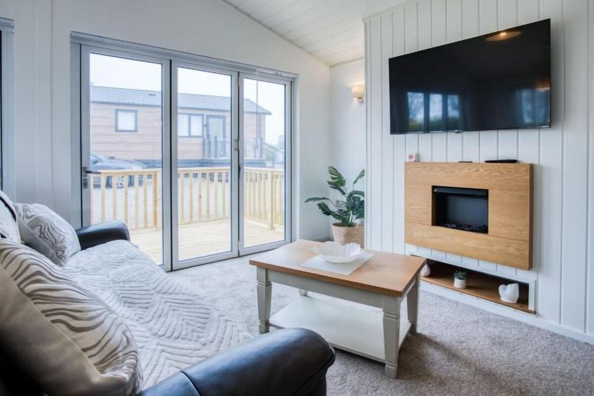 A living room with a sofa, a coffee table, a TV mounted on the wall, and a fireplace.