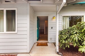 A house with a front porch, a door leading to an interior, and a small outdoor light fixture.
