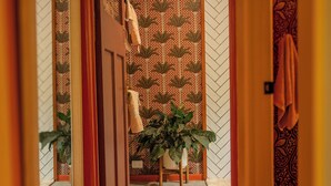 A hallway with a patterned wall, a potted plant, and a towel hanging on the wall. - Luxury Rainforest Studio with Moroccan-Inspired Design & Lush Gardens (Kuranda)