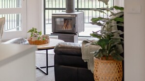 Una sala de estar moderna con chimenea, ventanas amplias y un balcón.
