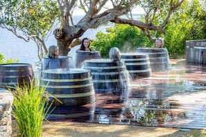 A water feature with barrels, a tree, and a body of water in the background.