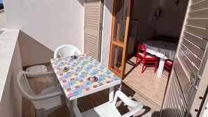 Ein Balkon mit Tisch und Stühlen, einer Schiebetür und einer kleinen Küchenzeile.