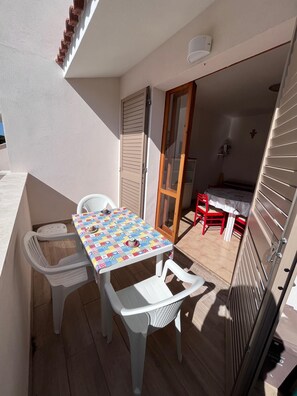 A balcony with a table and chairs, a sliding door, and a small kitchen area. - Only 150 meters from the sea, with terrace (Marcelli)
