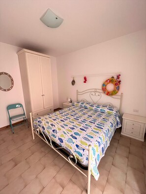 Une chambre à coucher comprenant un lit, une armoire, une chaise, une table de chevet et un élément décoratif fixé au mur.