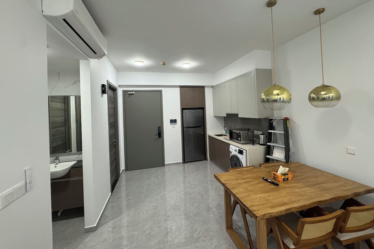 Una cocina moderna con horno integrado, microondas y cafetera. Hay una mesa de comedor de madera con sillas.