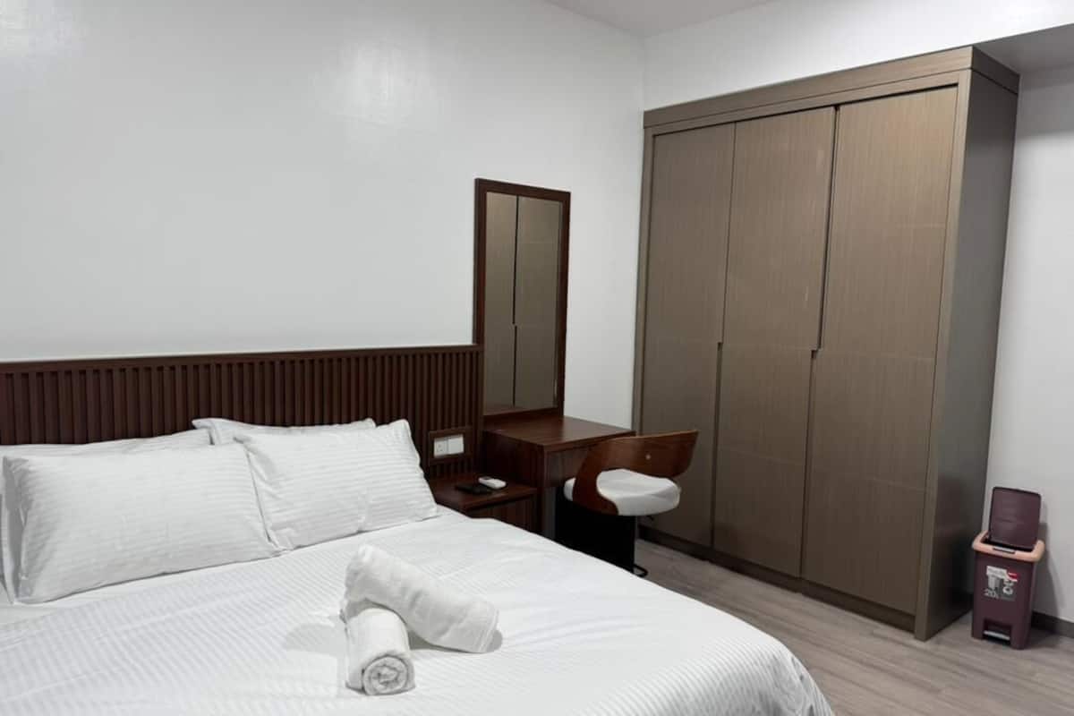 Ein Hotelzimmer mit Bett, Schreibtisch, Stuhl, Kleiderschrank und Mülleimer.