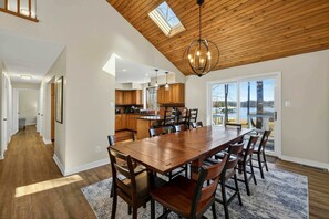 A spacious dining area with a wooden ceiling, a large table, and chairs.