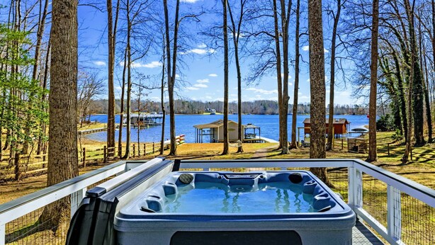 Un bain à remous avec vue sur un lac et un quai, entouré d’arbres.