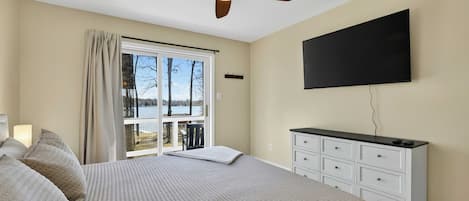 Upper Bedroom - A wall-mounted TV and dresser round out the room, with lake and deck views through the sliding door.