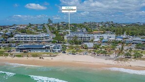 A coastal hotel with a beach view, multiple buildings, and a sign indicating 'Holiday Management.' - Coastal Calm at Paradiso - 231 (Tweed)