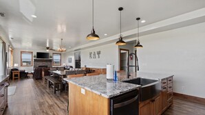 A spacious kitchen with granite countertops, wooden cabinets, and pendant lighting.