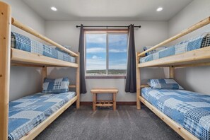 Una habitación con dos literas, una mesita de madera y una ventana con vistas.