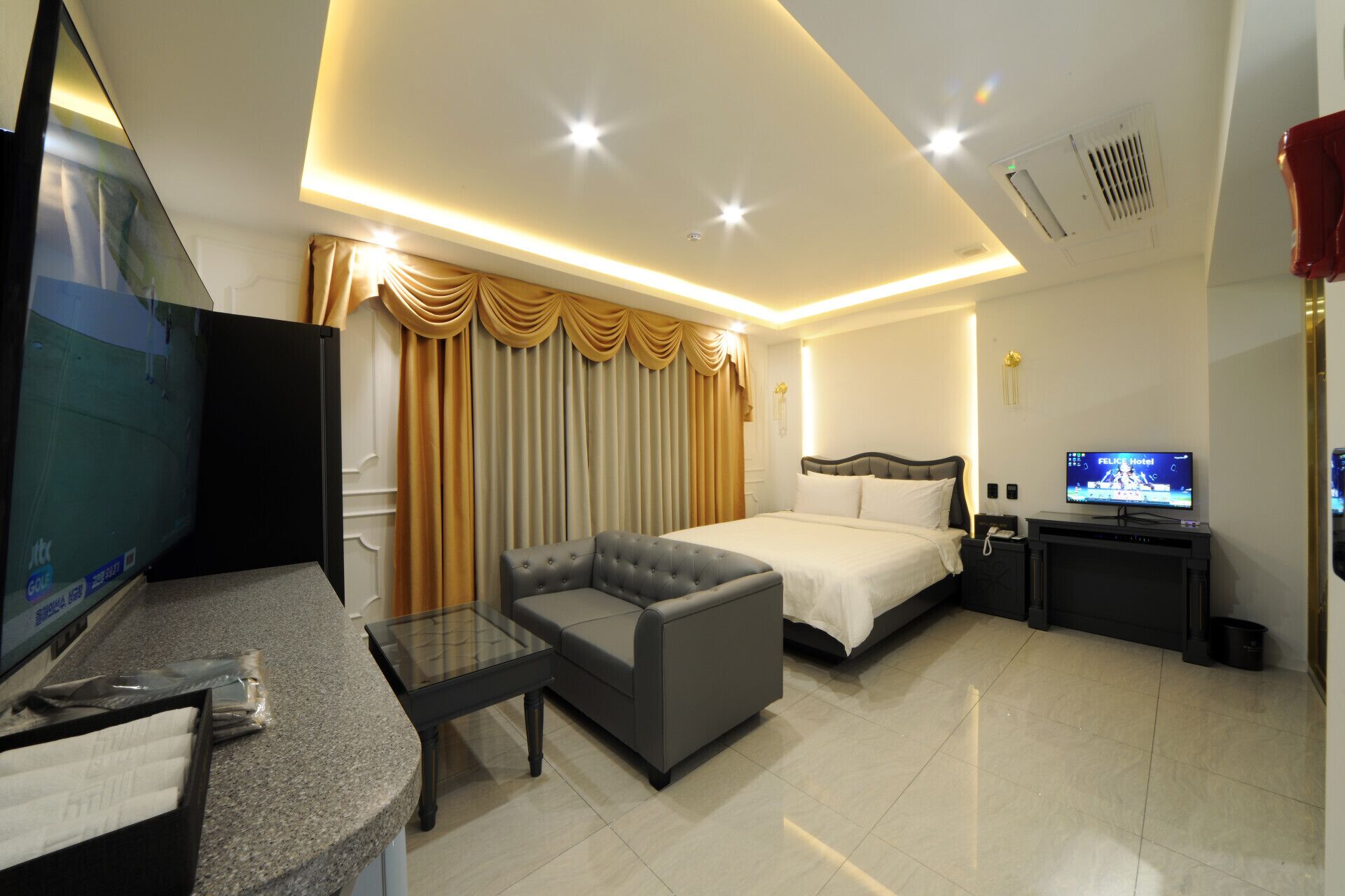 A hotel room with a bed, a sofa, a TV, and a desk.