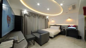 Una habitación de hotel moderna con cama, sofá, televisor y escritorio.