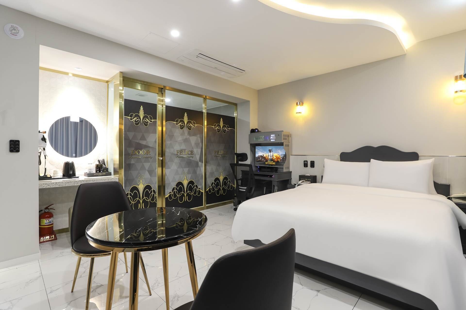 A hotel room with a bed, a desk with a computer, a TV, and a chair.