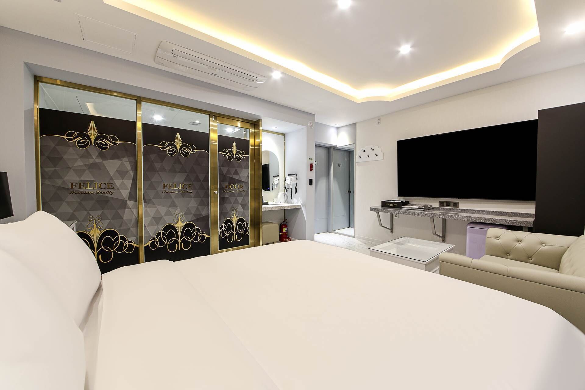 Una habitación de hotel moderna con una cama grande, un sofá, un televisor y un minibar.