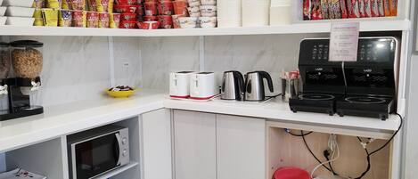 Una cocina compacta equipada con microondas, tostadora, hervidor y cafetera.