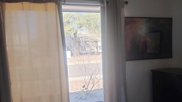 A room with a bed, a window with curtains, a painting on the wall, and a dark piece of furniture. - Tranquil 1-bedroom house with AC in charming Tucson (Tucson)