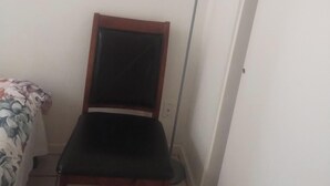 A room with a wooden chair, a standing floor lamp, and a partially visible bed with a floral bedspread. - Tranquil 1-bedroom house with AC in charming Tucson (Tucson)