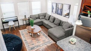 Uma sala de estar moderna com um sofá seccional, uma mesa de centro redonda, um tapete pequeno e uma bancada de granito.