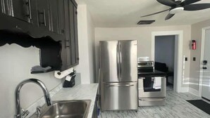 Una cucina moderna con elettrodomestici in acciaio inossidabile, una ventola a soffitto e un piano di lavoro in marmo.