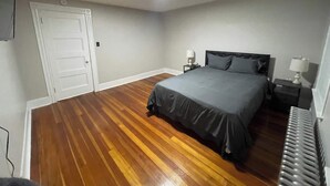 Una camera da letto con un letto, comodini, una scrivania e un termosifone.