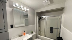 Un bagno con lavandino, specchio, toilette e cabina doccia in vetro.