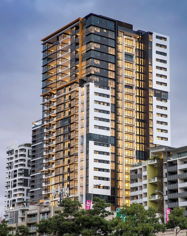 A multi-story hotel with balconies, a rooftop garden, and a sign indicating it is a hotel. - Stylish 1BR Executive Apartment with Pool & Gym (South Brisbane)