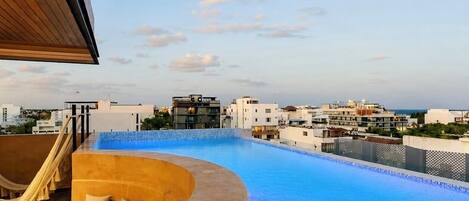 A rooftop infinity pool with a view of the city skyline.