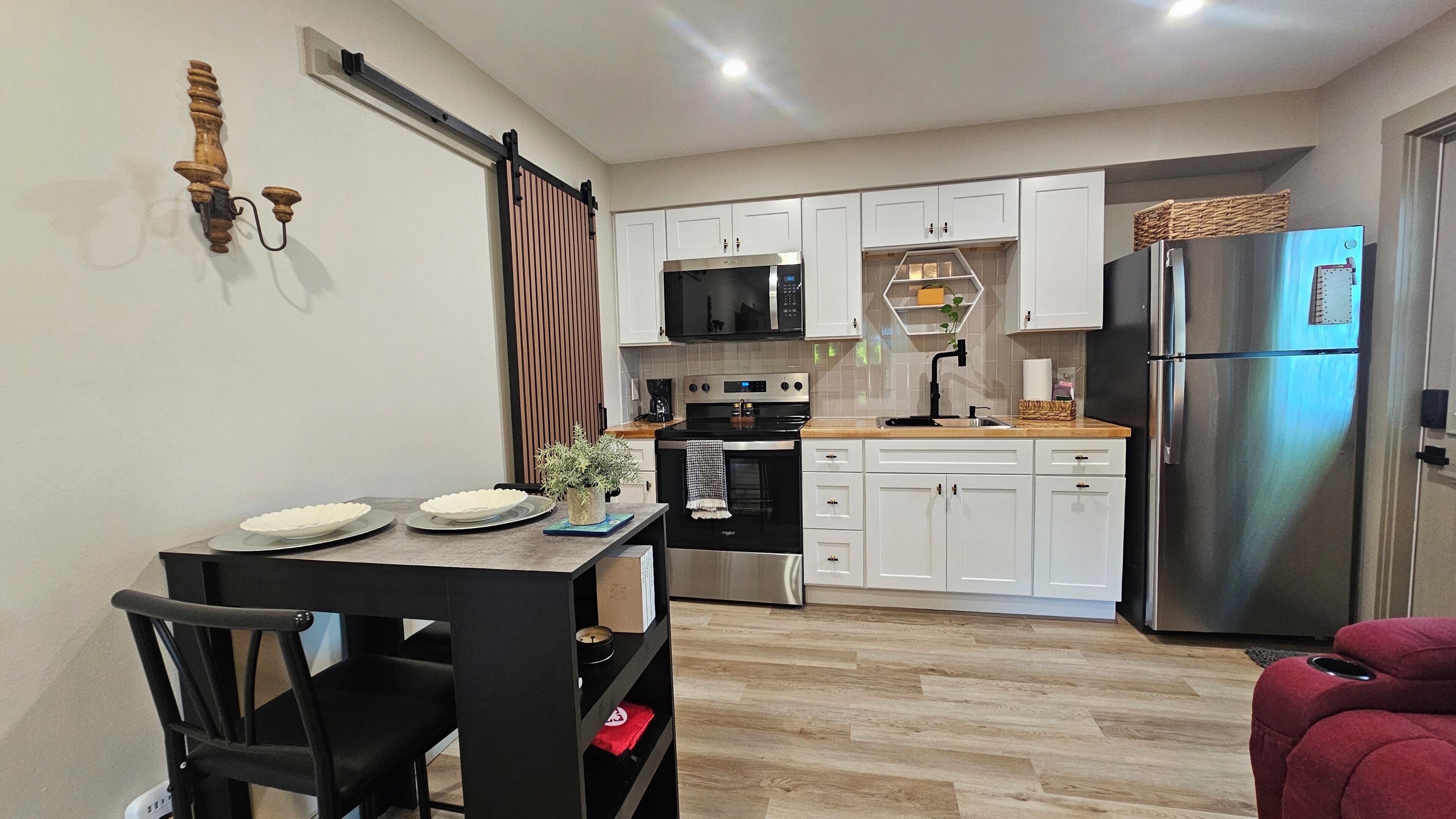 Una cocina moderna con armarios blancos, un refrigerador de acero inoxidable y un microondas.