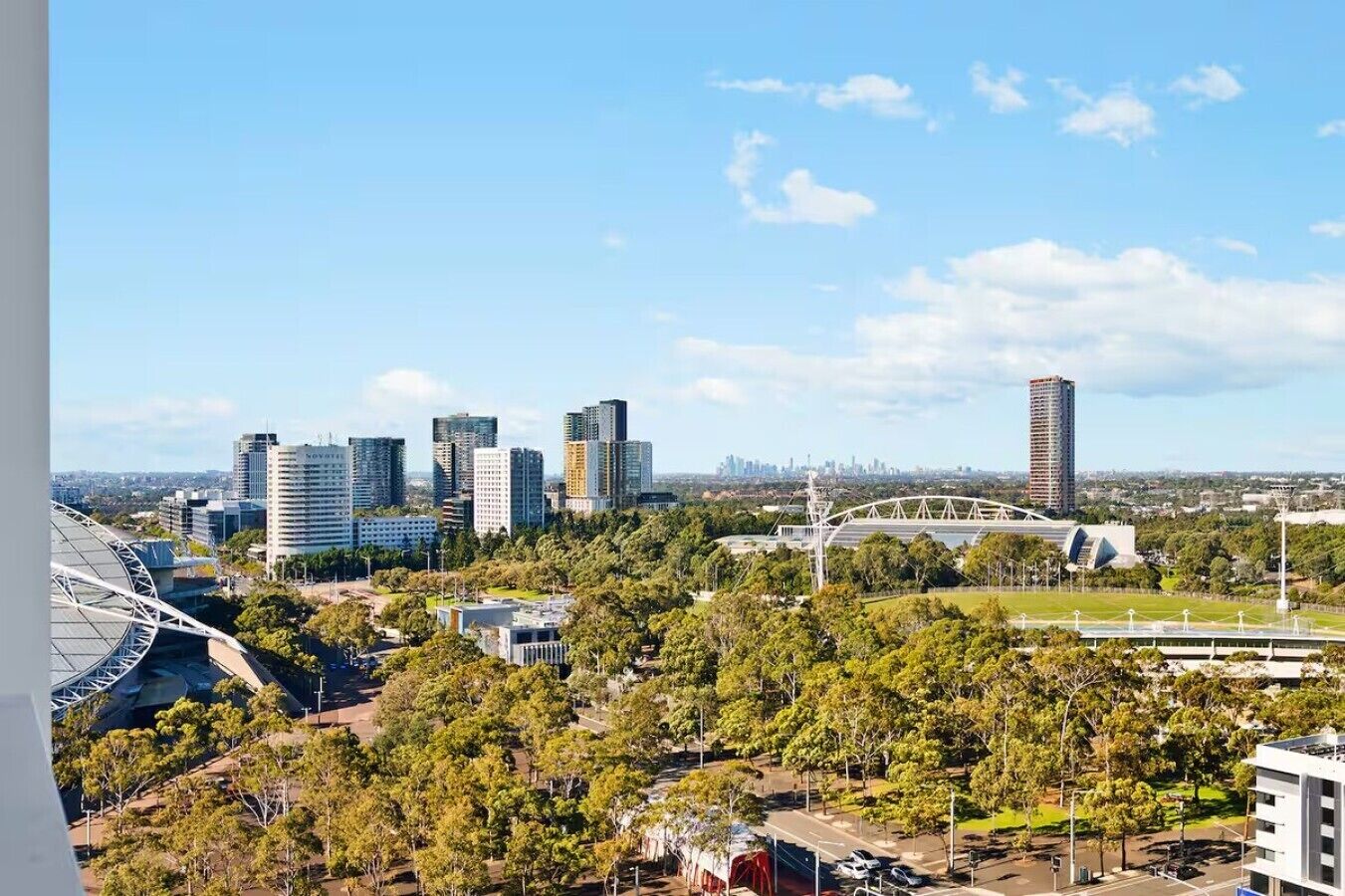 A cityscape with modern buildings, a bridge, and a stadium.