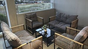 Un balcón con sofá, sillas y una mesa de centro.