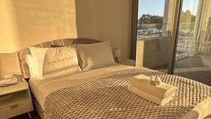 Un dormitorio moderno con una cama grande, una mesita de noche y vistas a través de un ventanal.