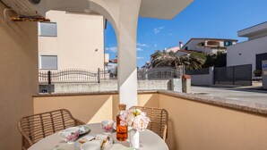 A balcony with a table set for two, featuring a vase with flowers, a bottle, and a plate of pastries. - Apt Rosa Walk To Beach /w Balcony (Medulin)