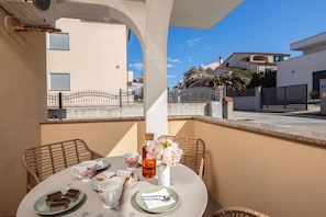 A balcony with a table set for two, featuring a vase with flowers, a bottle, and a plate of pastries. - Apt Rosa Walk To Beach /w Balcony (Medulin)