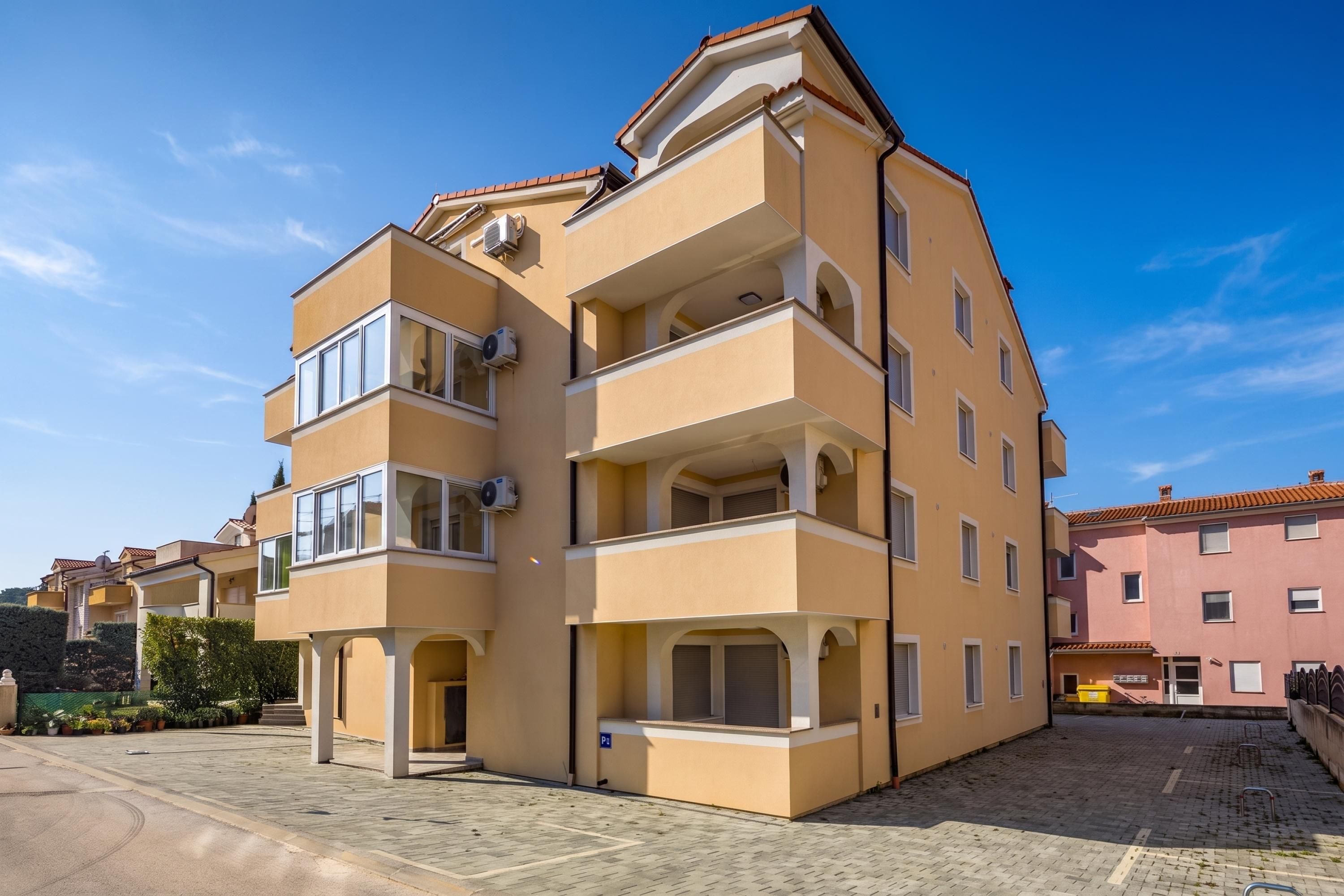 A multi-story residential building with balconies and air conditioning units.