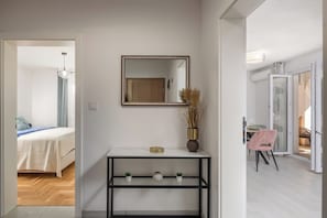 A hotel room with a bed, a console table, a mirror, and a view of the balcony. - Apt Rosa Walk To Beach /w Balcony (Medulin)