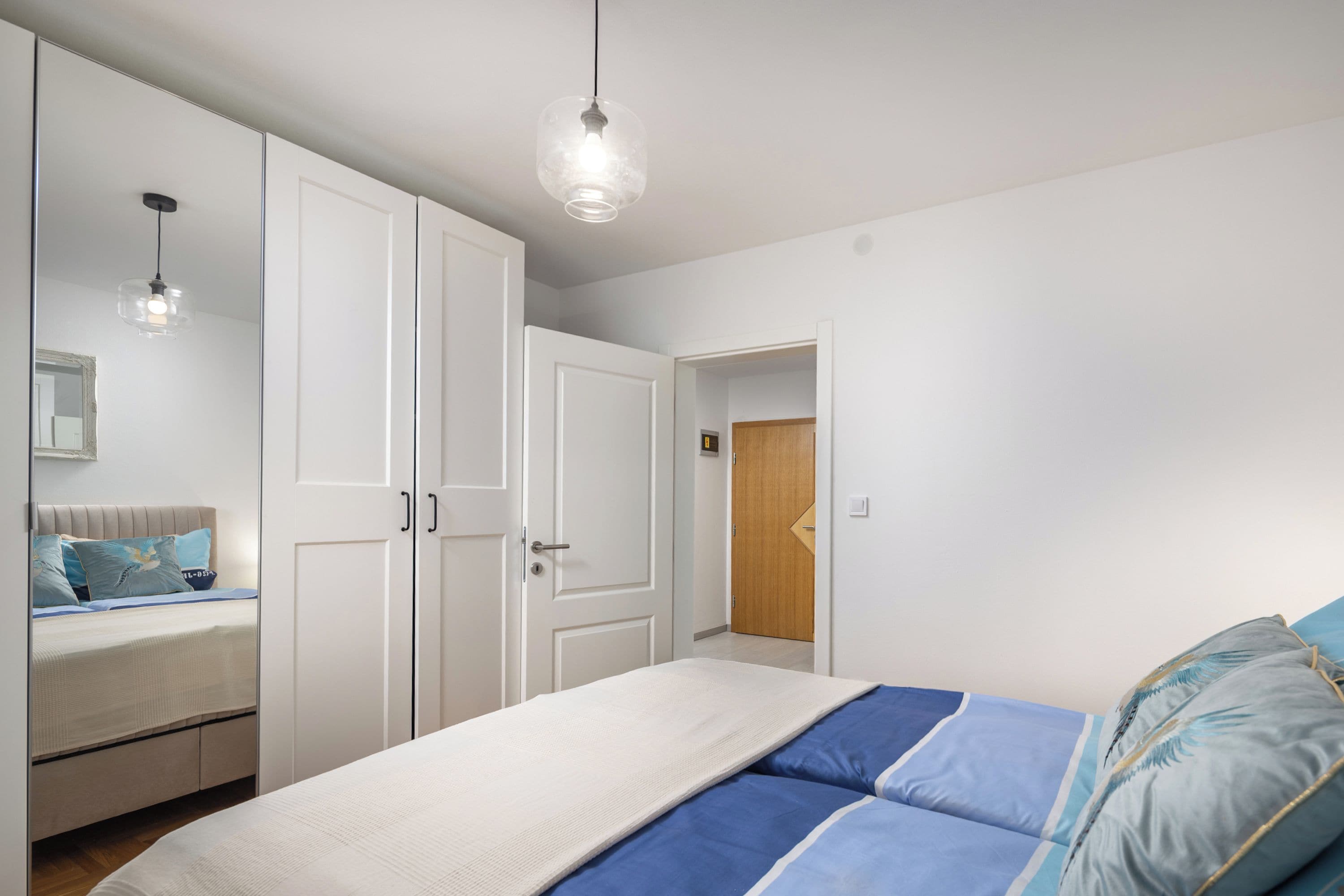A bedroom with a bed, wardrobe, and a mirror.