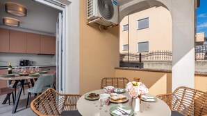 A dining area with wicker chairs, a round table, and a view of the building's exterior. - Apt Rosa Walk To Beach /w Balcony (Medulin)