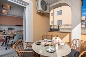 A dining area with wicker chairs, a round table, and a view of the building's exterior. - Apt Rosa Walk To Beach /w Balcony (Medulin)